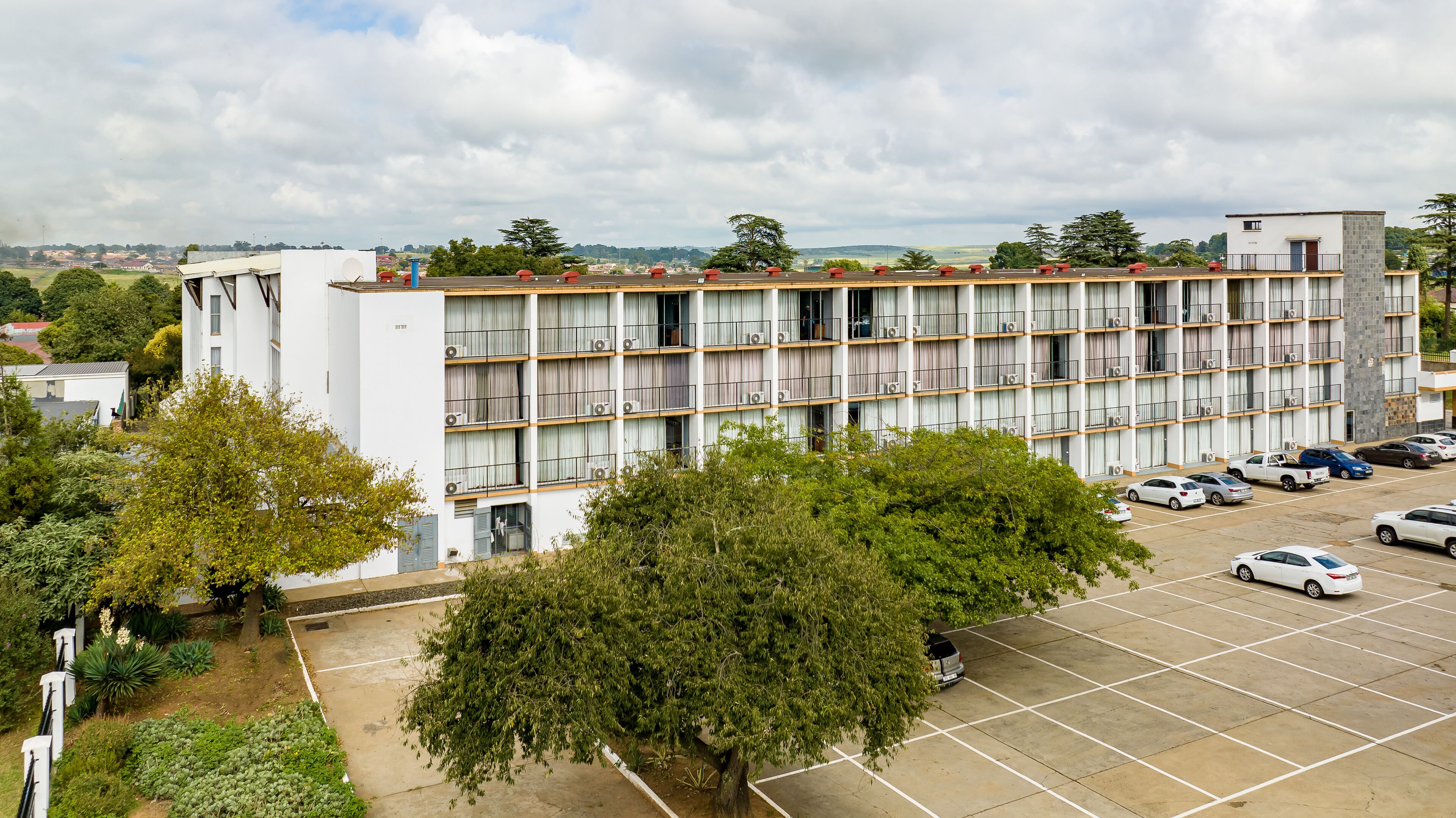 A multi-story hotel with a parking lot in front.