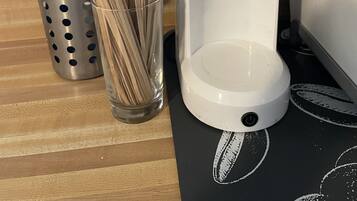 En kaffemaskin med etiketten ”MIXPRESSO” står på en bänkskiva, bredvid den finns en metallkorg med kaffekapslar och ett glas med sugrör.
