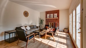 A living room with a sofa, coffee table, and chairs, a fireplace, and a large window.
