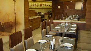 A restaurant with multiple dining tables set for service, equipped with cutlery and glasses. - King's Kraft Stay Inn Rajkot (Rajkot)