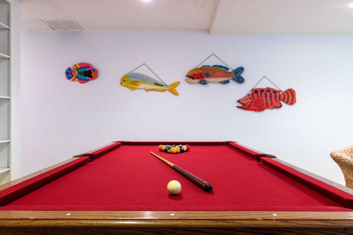 Une table de billard recouverte d’un drap de feutre rouge, une queue de billard et une bille blanche.
