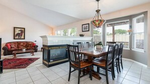 A spacious living room with a large sofa, a dining table with chairs, and a kitchen area with a white countertop and hanging light fixture. - Wasatch Oaks Retreat (Cottonwood Heights)