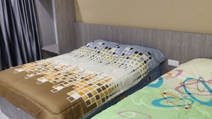 Hotelkamer met een bed, nachtkastje, plafondventilator en raam met gordijnen.