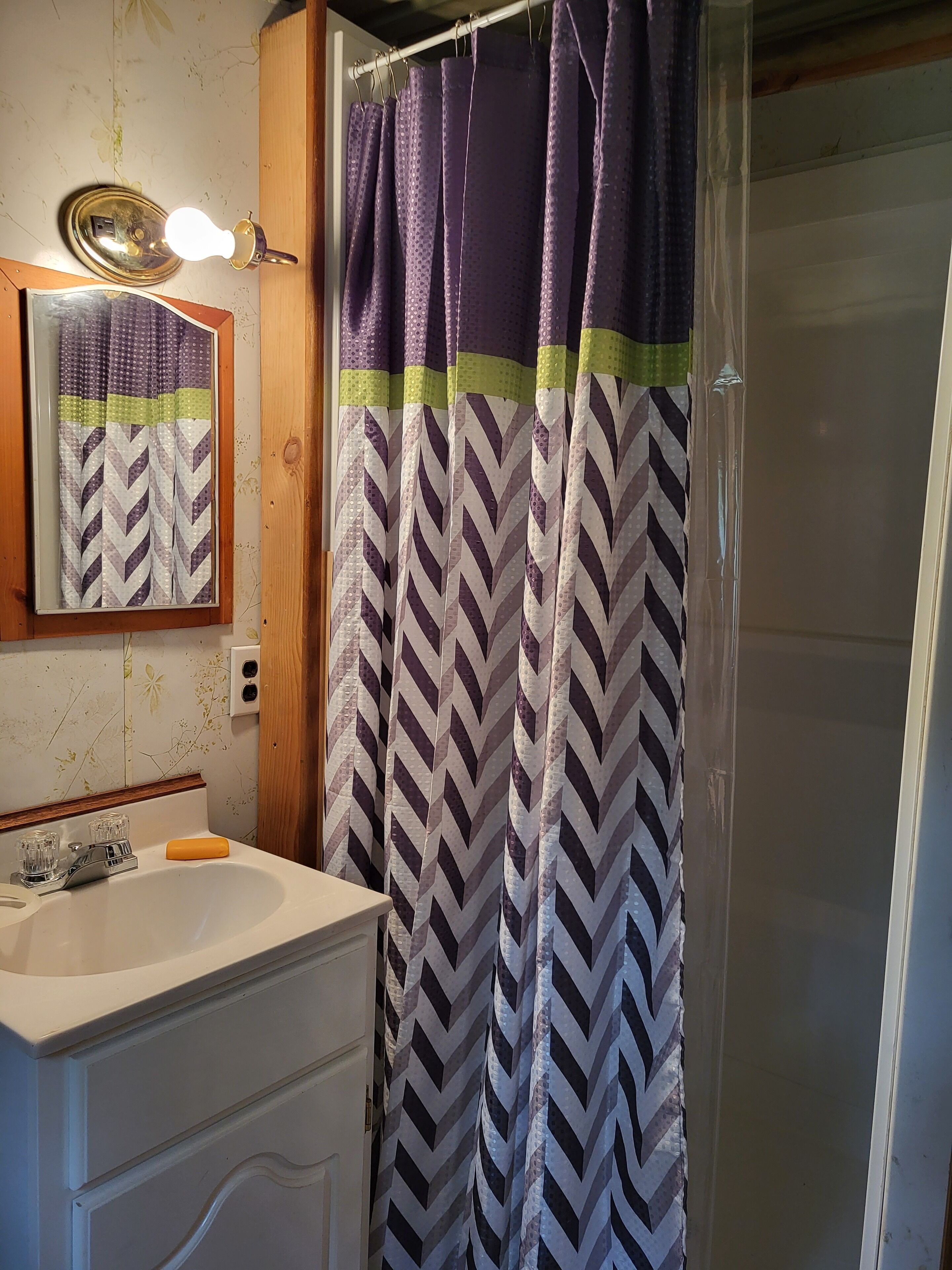 A bathroom with a sink, mirror, and shower curtain.