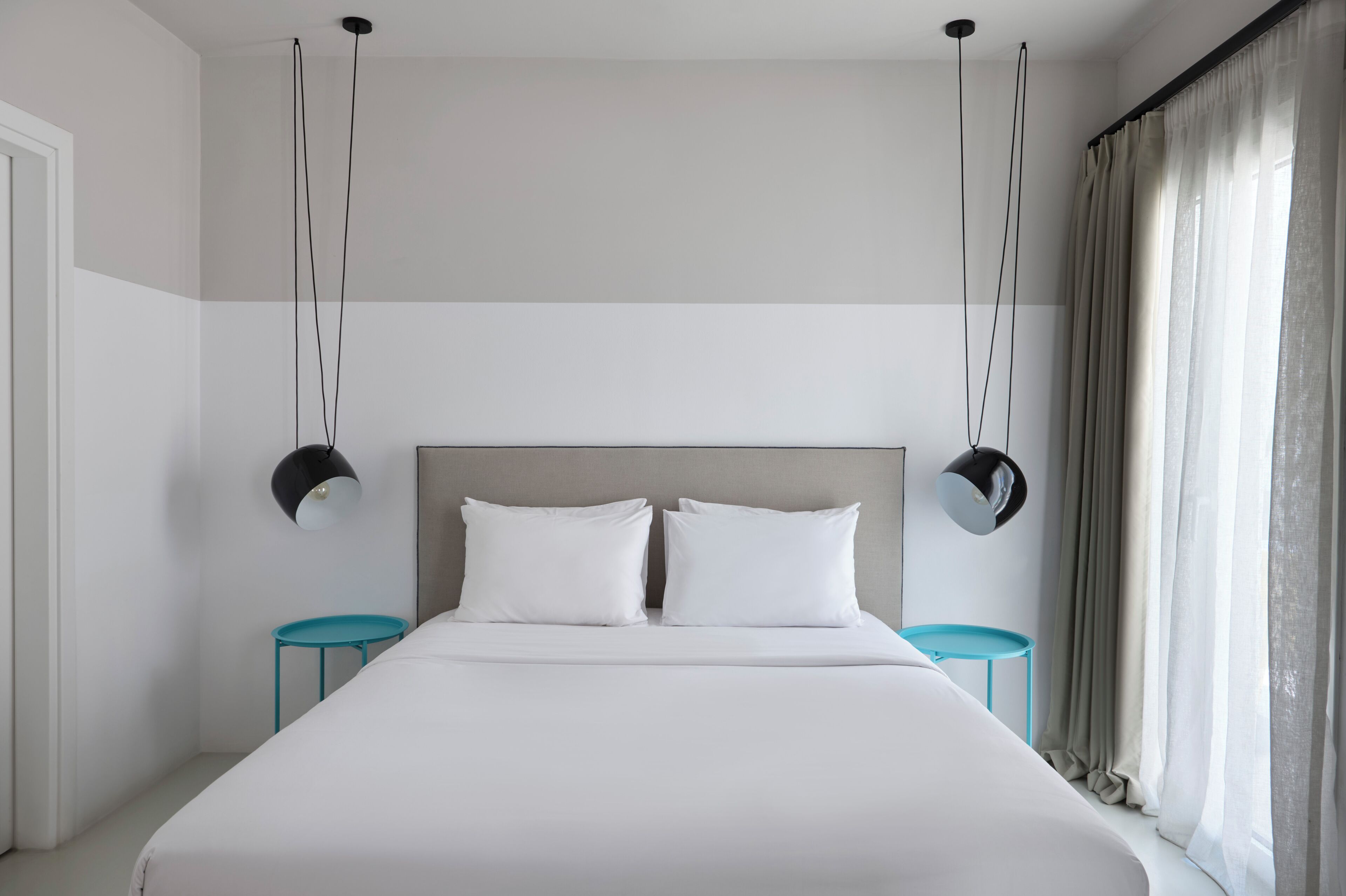 A modern hotel room with a large bed, two bedside tables, and a headboard.