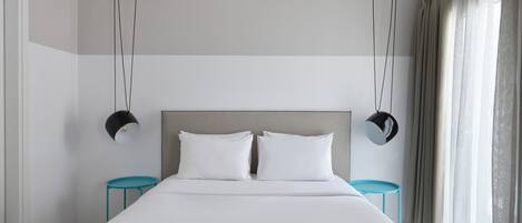 Habitación de hotel moderna con una cama grande, dos mesitas de noche y un cabecero.
