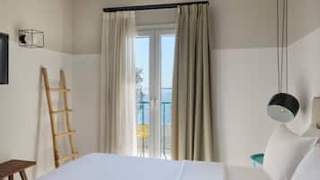 Habitación de hotel con cama, escalera de madera, ventana con cortinas y vista al exterior.