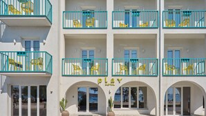 A hotel with multiple balconies, each with yellow chairs and blue railings. - Play Paros, a member of Brown Hotels (Paros)