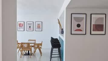 A modern interior with a dining area, a staircase, and abstract art on the walls.