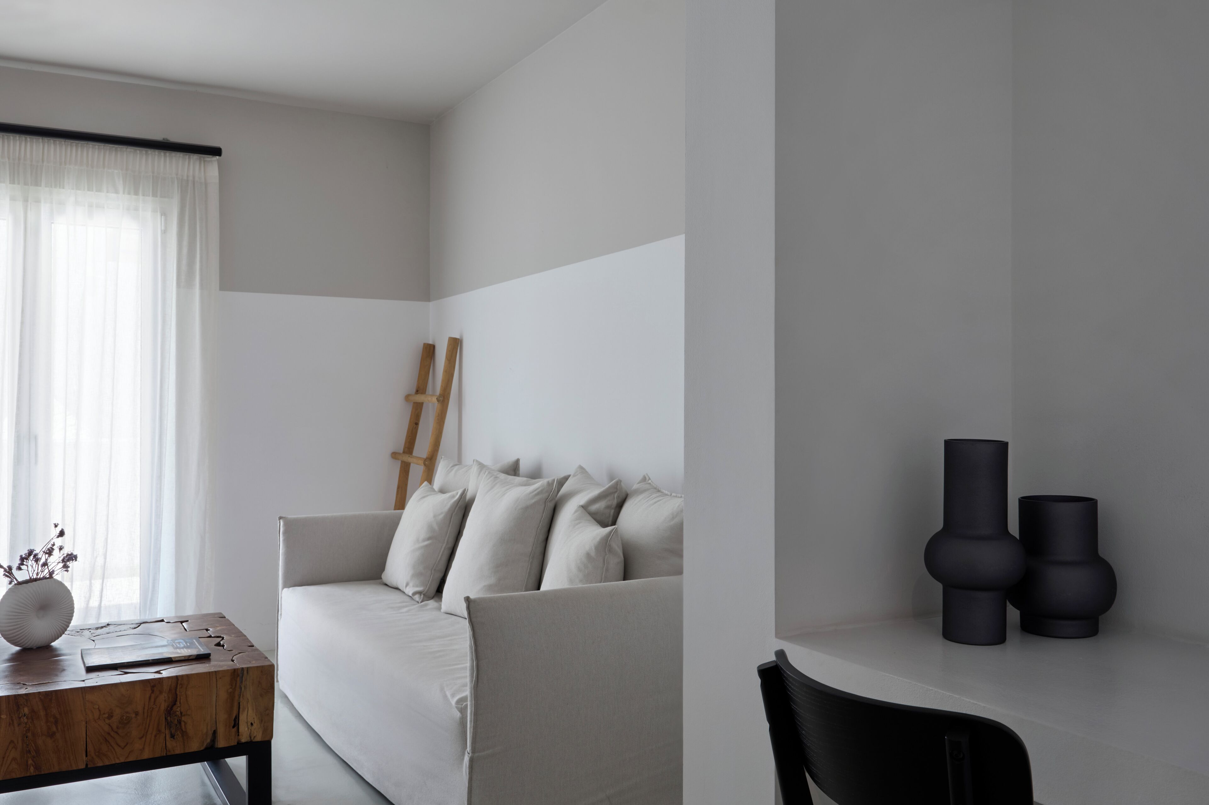 Un salon minimaliste avec un canapé, une petite table en bois et une chaise noire.