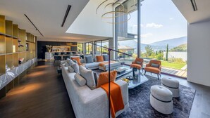 A modern living room with a large sofa set, a coffee table, and a view of the outdoors. - Villa Tomar (Talloires-Montmin)