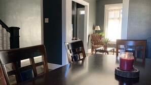 Un coin repas avec une table en bois foncé, deux chaises, une plante en pot et une bougie allumée.