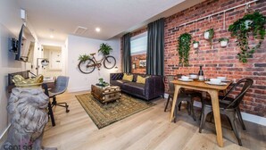 Een moderne woonkamer met een bakstenen muur, een bank, een eettafel en een aan de muur bevestigde fiets.