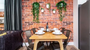 Een eetgedeelte met een bakstenen muur, hangplanten en een moderne tafel voor vier personen.