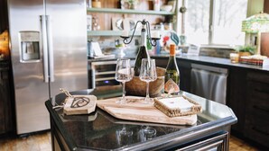 Una encimera de cocina con dispensador de agua, copas de vino y una botella.