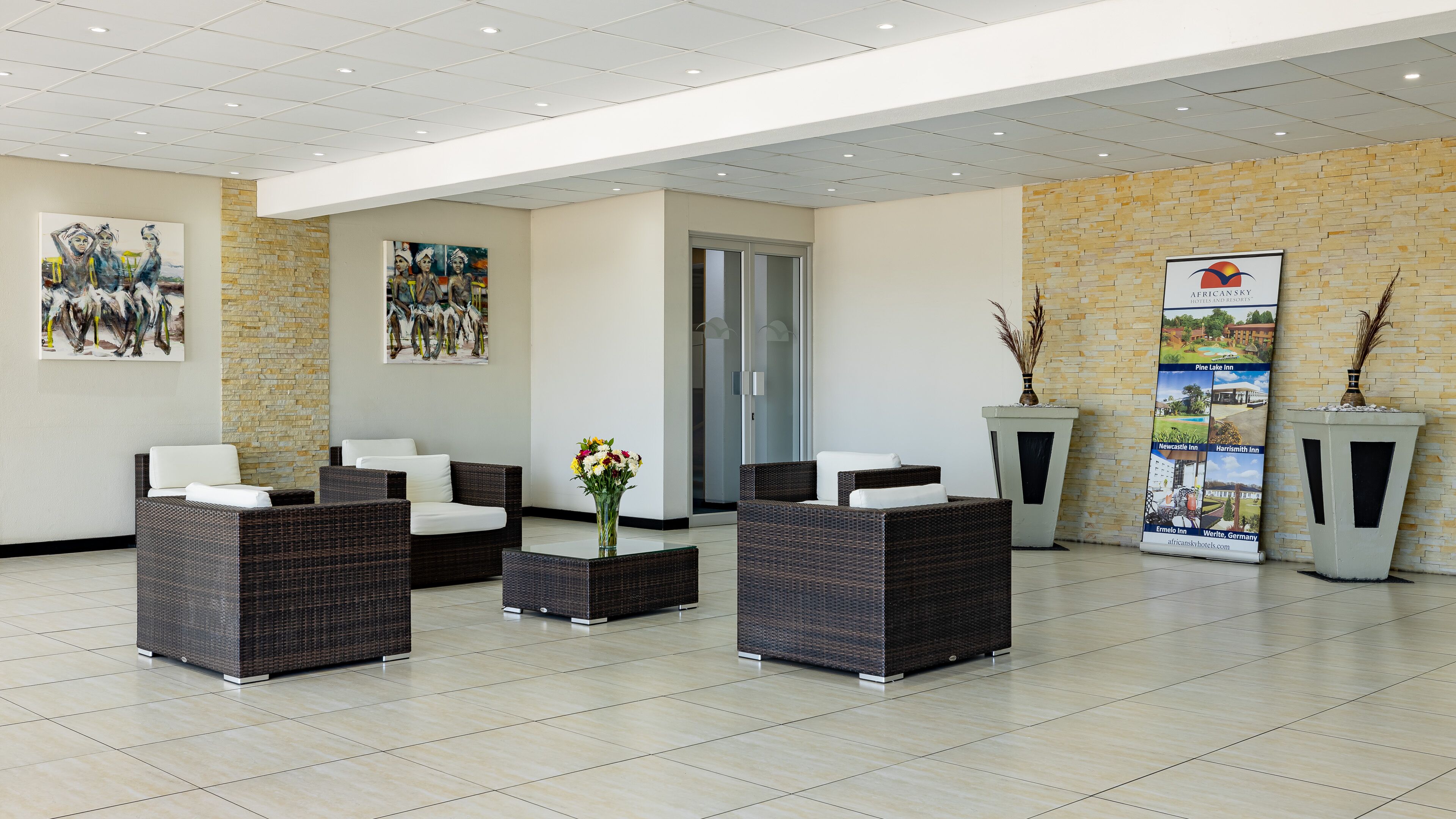 En moderne lobby med fletningsmøbler, en glasdør og kunst på væggene.