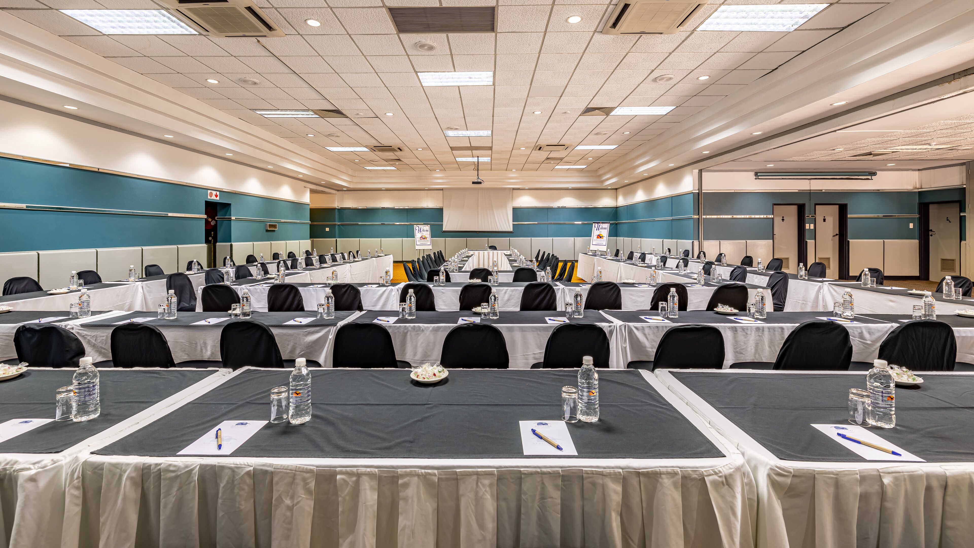 A conference room with multiple tables, chairs, and water bottles.