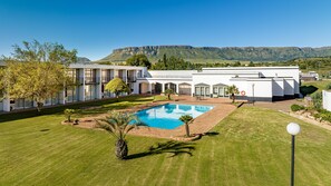 A modern hotel with a swimming pool, well-maintained lawn, and mountain views. - African Sky Hotels - Harrismith Inn (Maluti a Phofung)