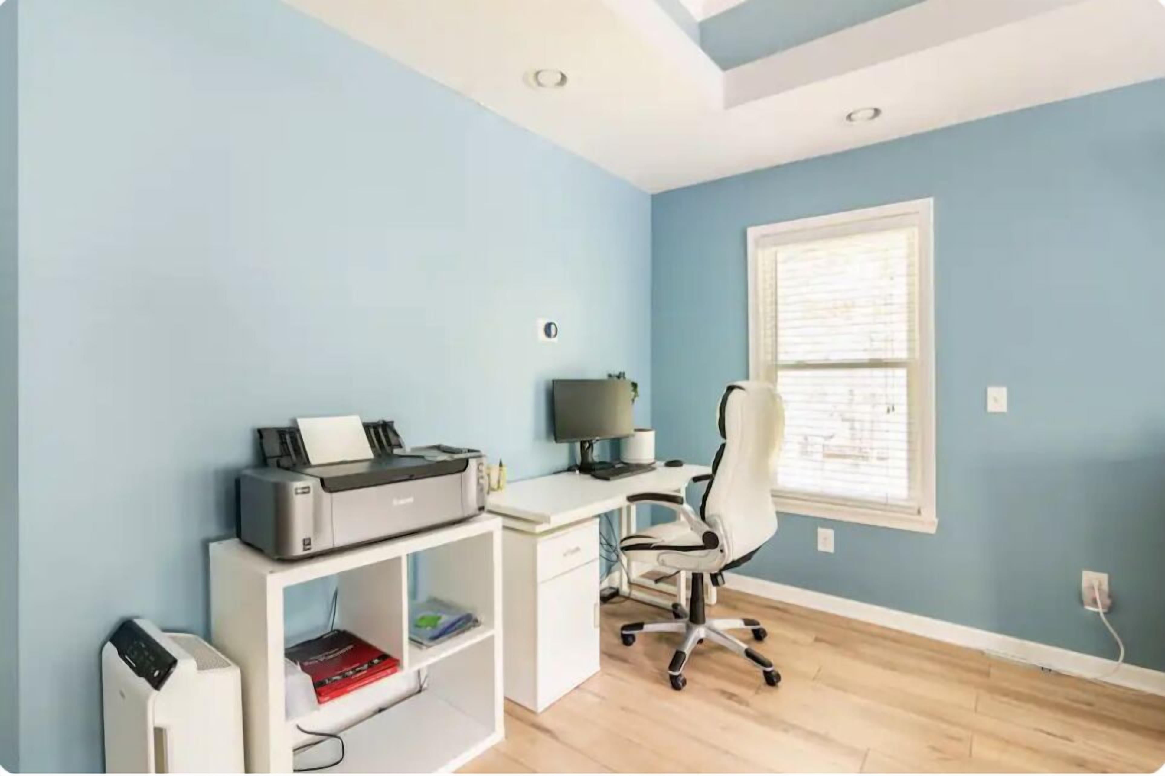 A room with a desk, printer, and office chair.