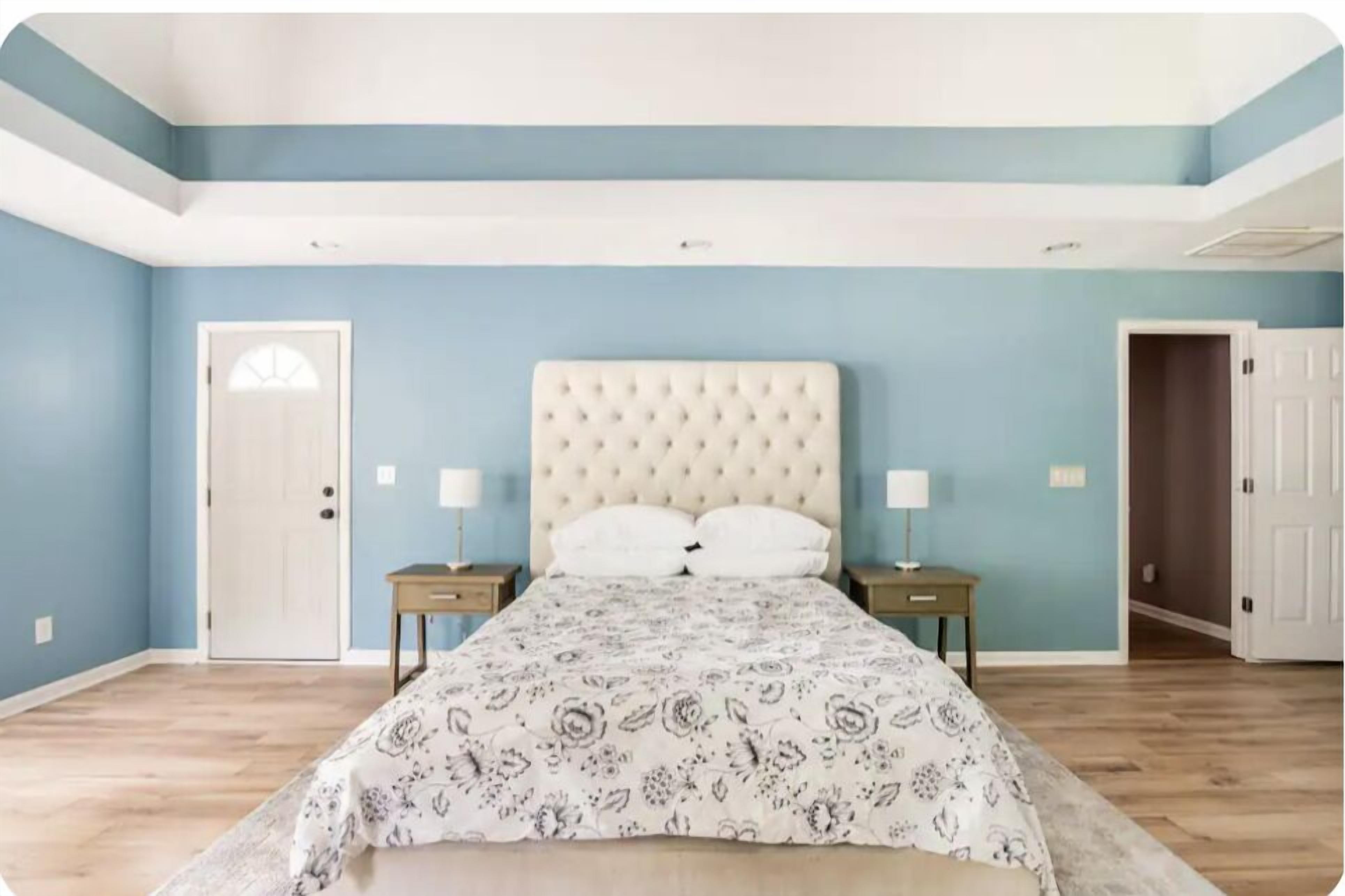 A bedroom with a bed, two bedside tables, and a door.