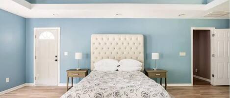 A bedroom with a bed, two bedside tables, and a door.