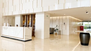 Un moderno vestíbulo de hotel con mostrador de recepción, zona de estar y un gran macetero negro.