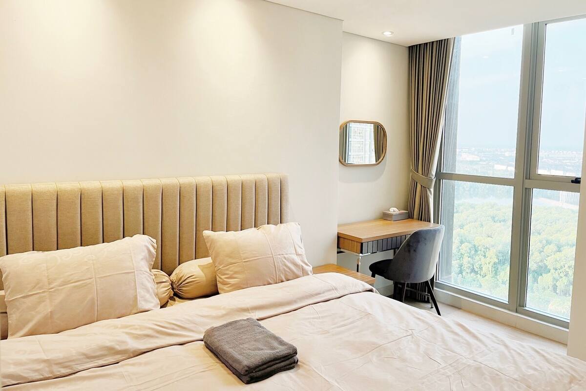 A hotel room with a large bed, a desk, and a view of the city.