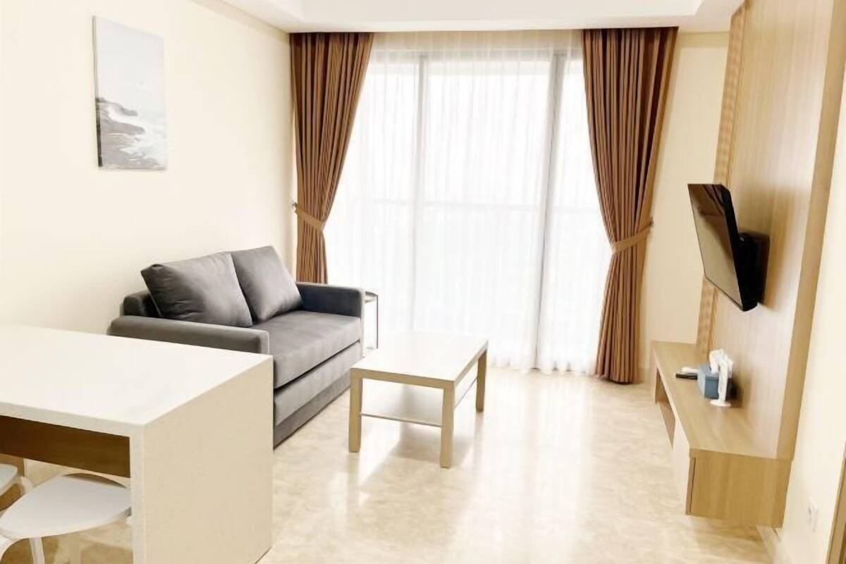 A modern living room with a grey sofa, a white coffee table, and a TV mounted on a wooden wall.
