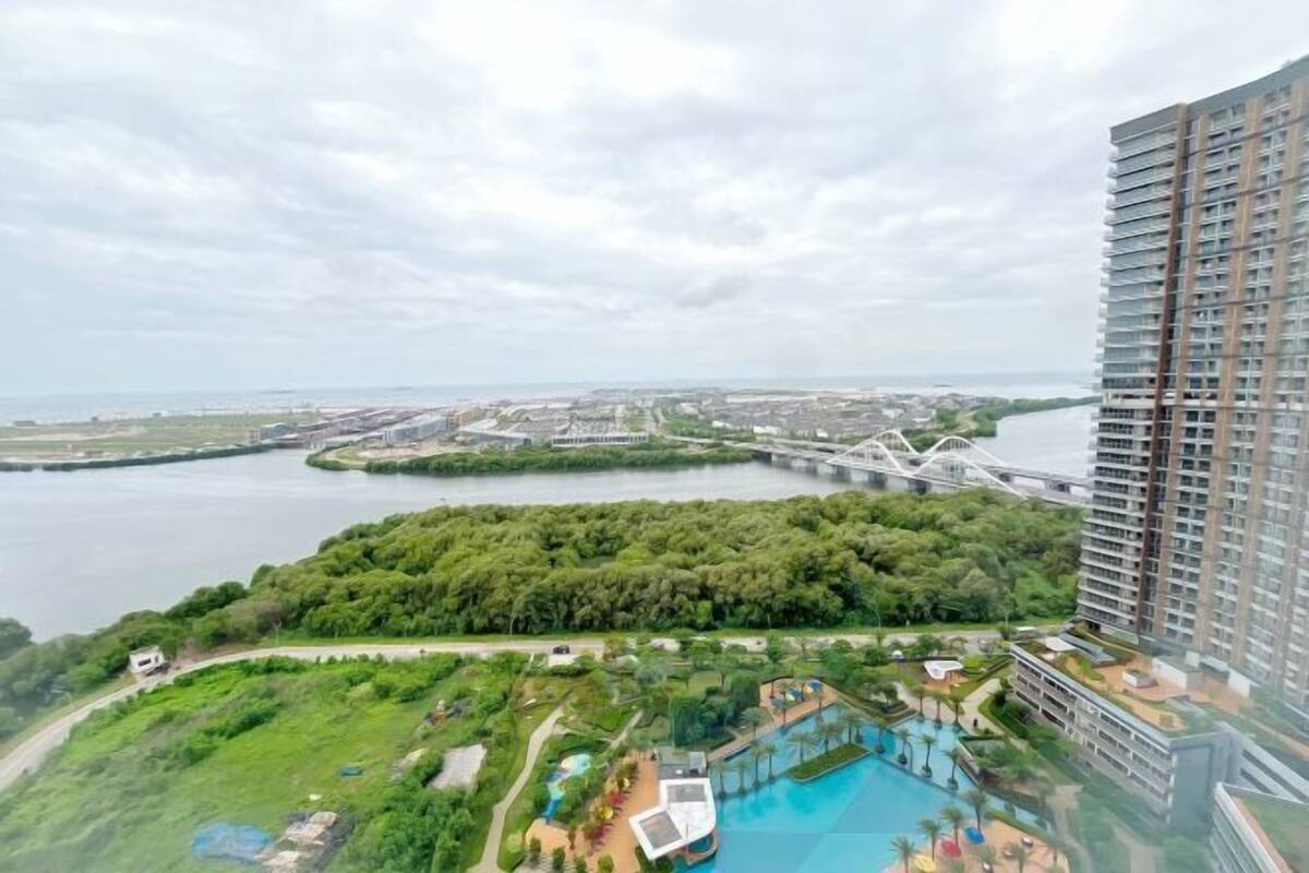 A high-rise hotel with a rooftop pool and lush greenery.