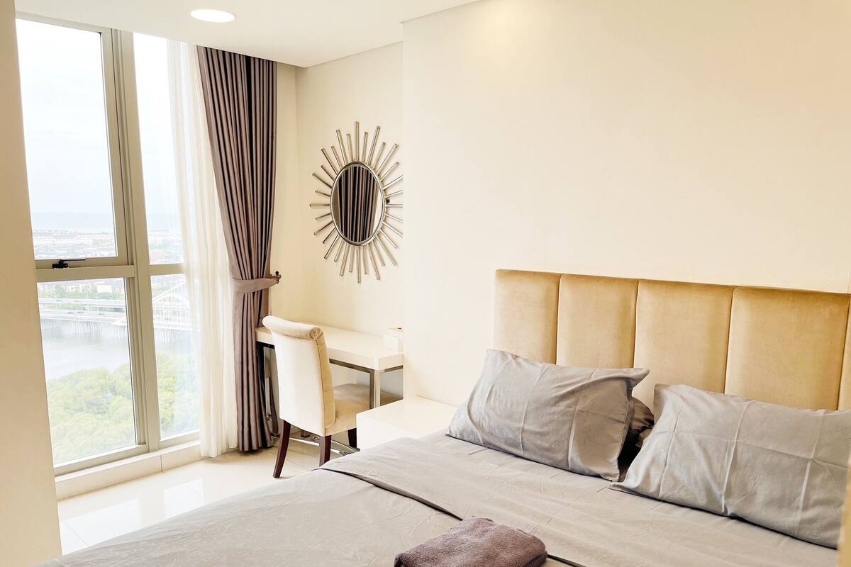 A hotel room with a large bed, a desk, and a view of a cityscape.