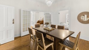 Comedor con una mesa de madera, seis sillas, una araña y un espejo grande en la pared.