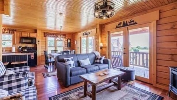 Interior acollidor d'una cabana amb menjador, saló amb sofà i taula de café, i cuina.