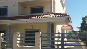 A two-story building with a tiled roof, a gated entrance, and a small balcony. - Alojamento dos Redondos (Fernão Ferro)