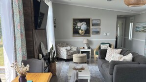 Ein modernes Wohnzimmer mit grauem Sofa, einem Holzesstisch und einem weißen Couchtisch.