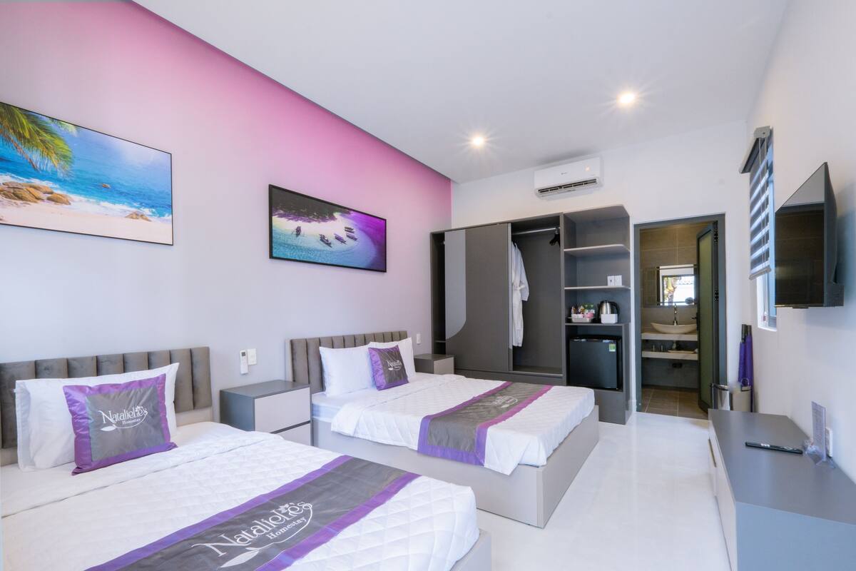 A hotel room with two beds, a wardrobe, a bathroom, and a TV.