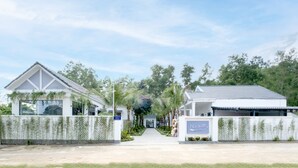 A hotel entrance with a pathway leading to the main building, surrounded by greenery and a clear sky. - NatalieLe's Homestay (Phu Quoc)