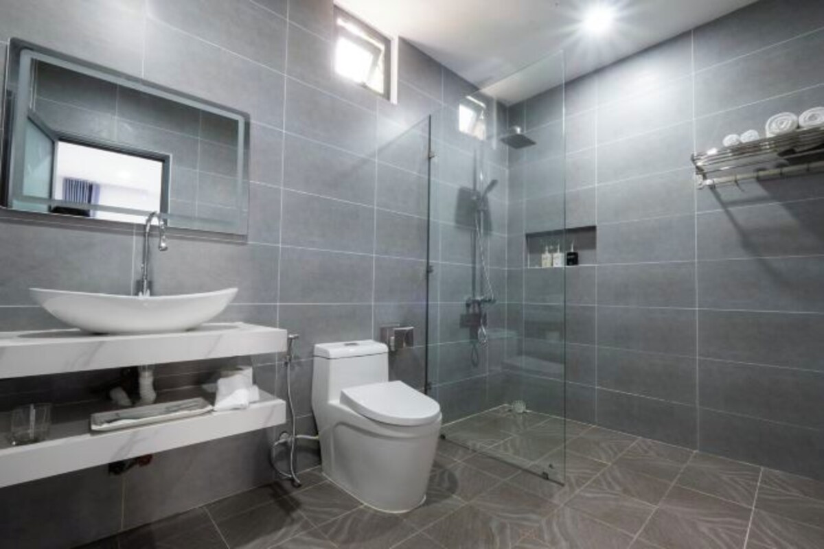 A modern bathroom with a large sink, toilet, and glass shower enclosure.