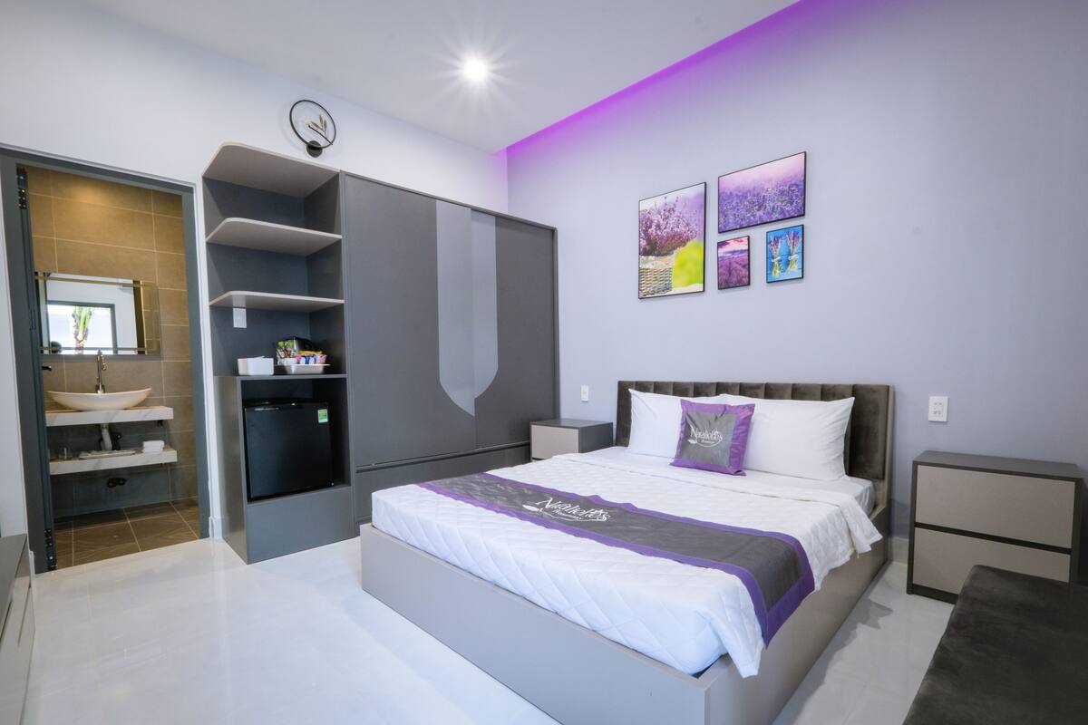 A modern bedroom with a large bed, built-in wardrobe, and a vanity with a sink.