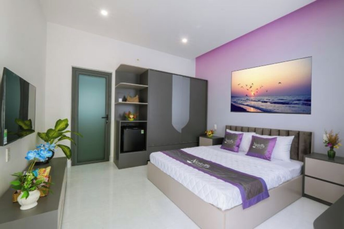 A modern bedroom with a bed, a wardrobe, a desk, and a nightstand.