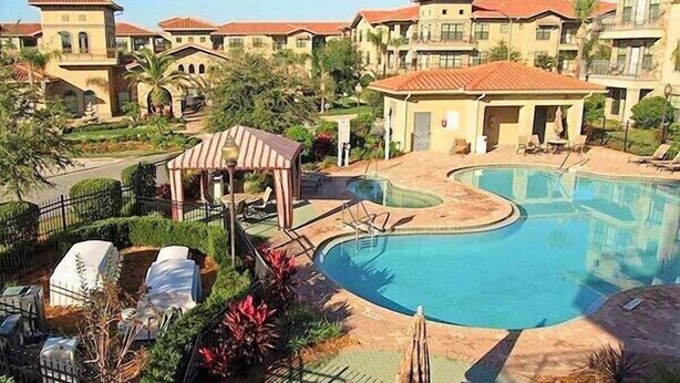 Een resort met een groot zwembad, ligbedden en een prieel.