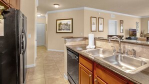 Een keuken met een koelkast, vaatwasser, dubbele spoelbak en houten kasten.