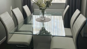 Una sala de reuniones moderna con una mesa de vidrio, sillas de cuero blanco y un jarrón de flores.