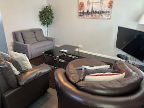 Un salon avec un canapé, une table basse, un téléviseur et un tableau accroché au mur.