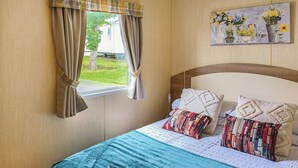 Una camera da letto con un letto, tende, una finestra e un quadro appeso al muro.