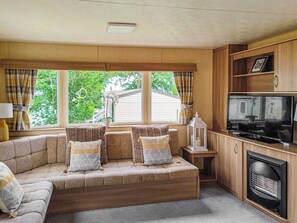 A cozy living room with a sectional sofa, a television, and a fireplace. - The Meadows is a great family property where you can enjoy a coastal break. (Wemyss Bay)