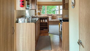 Una cucina compatta con mobili in legno, un tostapane, un bollitore e un estintore.