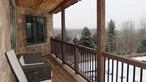 Eine Holzterrasse mit einer Steinmauer und Blick auf eine verschneite Landschaft.