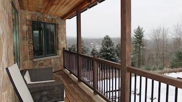 Une terrasse en bois, un mur en pierre et une vue sur un paysage enneigé.