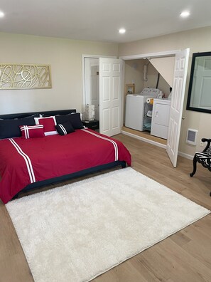 Quarto com cama, tapete branco, guarda-roupa e espaço para lavanderia.