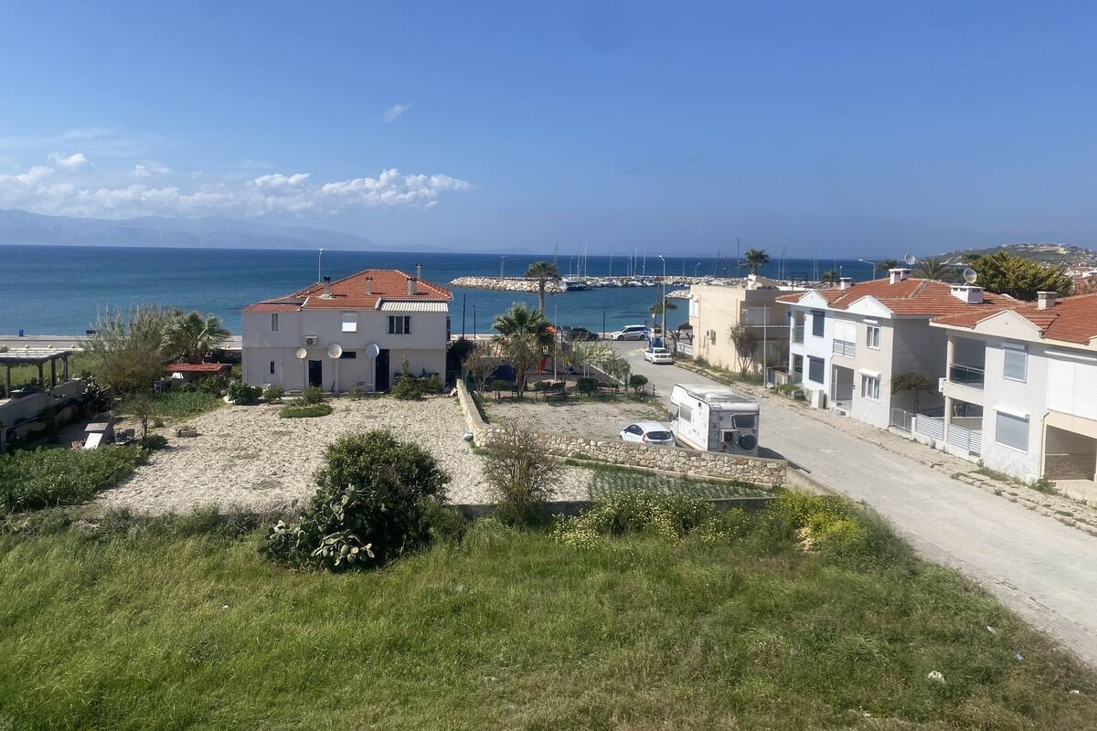 A coastal residential area with houses, a marina, and a clear view of the sea.